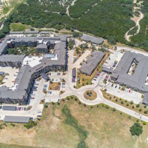 Aerial view of a large building complex surrounded by greenery and open fields.