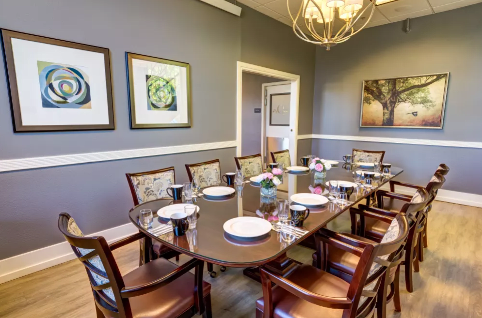 A well-decorated dining room with a large table set for a meal, featuring artwork and a chandelier.
