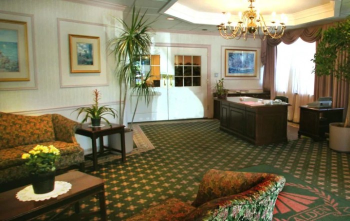 A cozy living room with patterned carpet, sofas, and decorative elements like indoor plants and artwork.