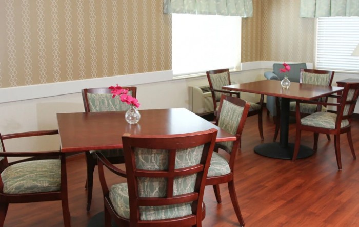 A cozy dining area with wooden tables and chairs, adorned with small flower decorations.