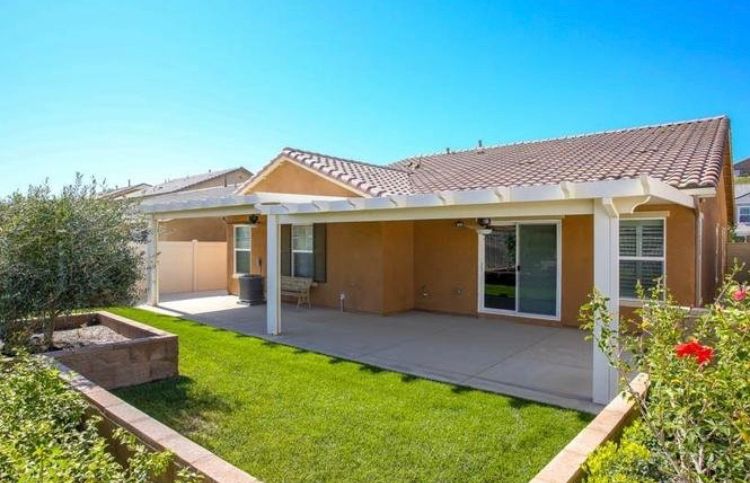 A sunny backyard with a patio and well-maintained lawn.