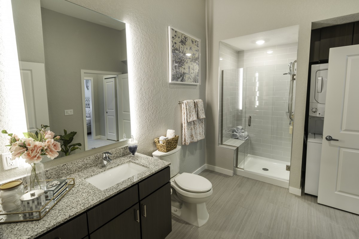 A modern bathroom featuring a stylish sink, toilet, and a glass-enclosed shower with contemporary lighting.