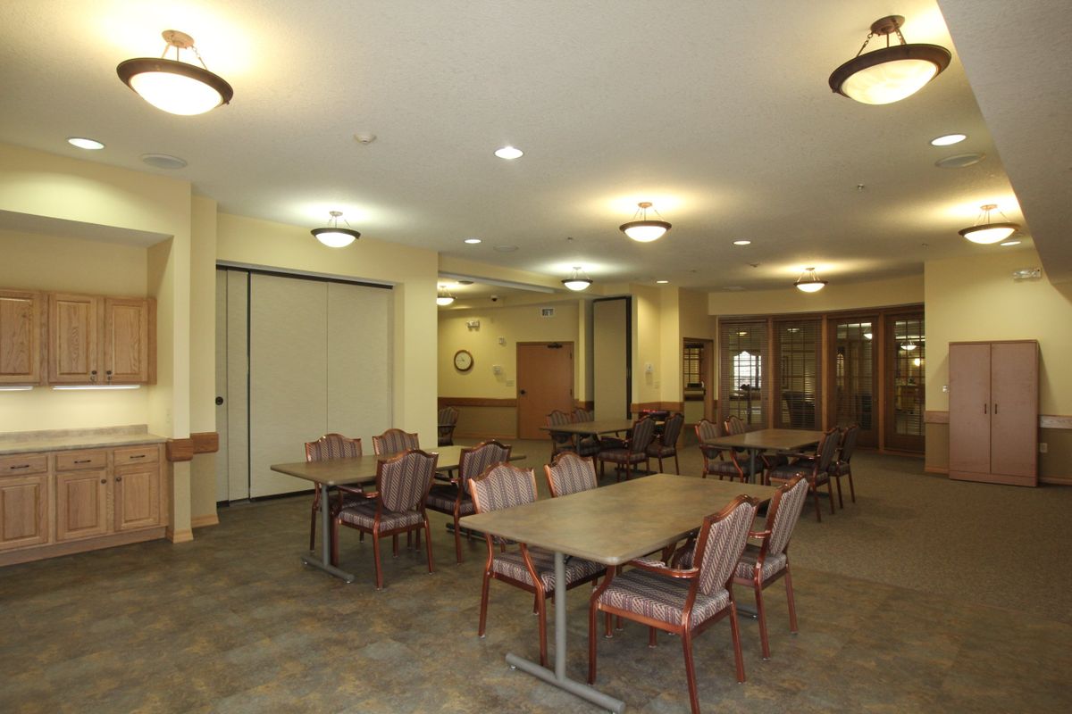 A spacious dining area with arranged tables and chairs, well-lit by ceiling fixtures.