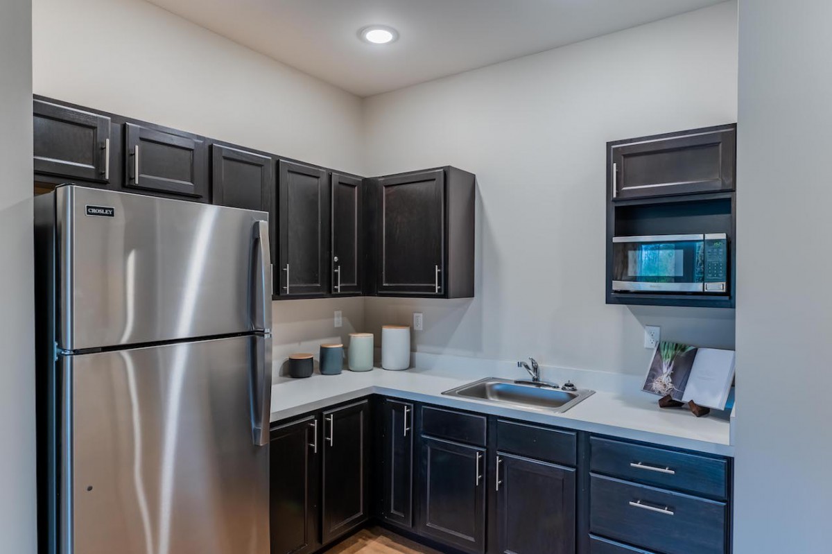 A modern kitchen featuring dark cabinets and stainless steel appliances.