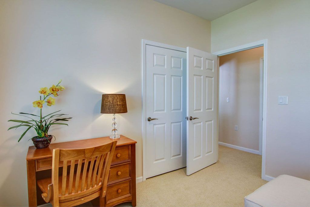 A cozy bedroom with a wooden desk, chair, and an open closet.