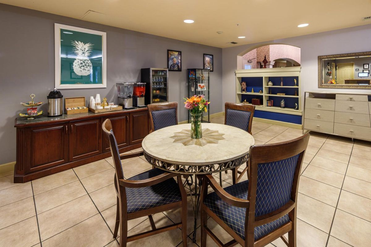 Cozy dining area with a round table and chairs, featuring a vase of flowers, surrounded by cabinets and a beverage station.