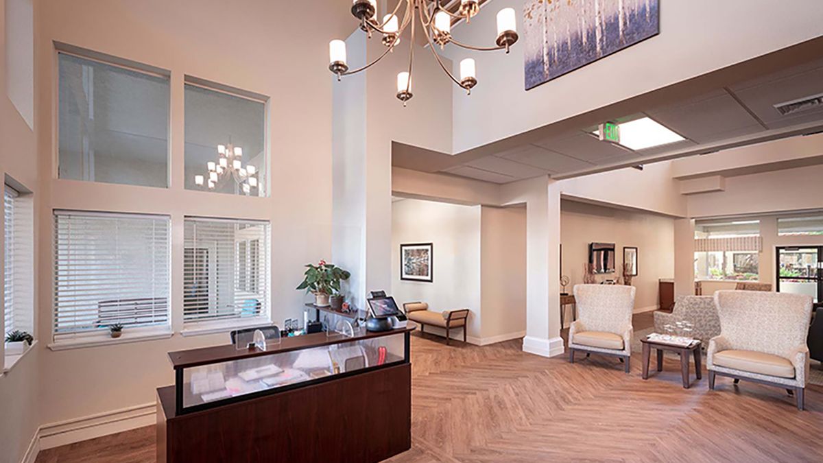 A modern reception area with a chandelier and seating.