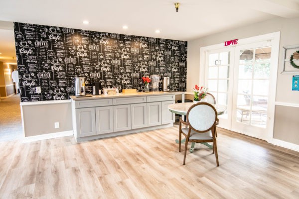 A modern kitchen interior with a coffee station, featuring stylish wallpaper and seating.