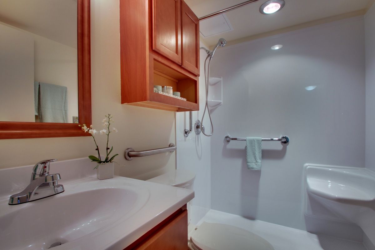 A modern bathroom featuring a clean shower area, sink with an orchid, and a wooden cabinet.