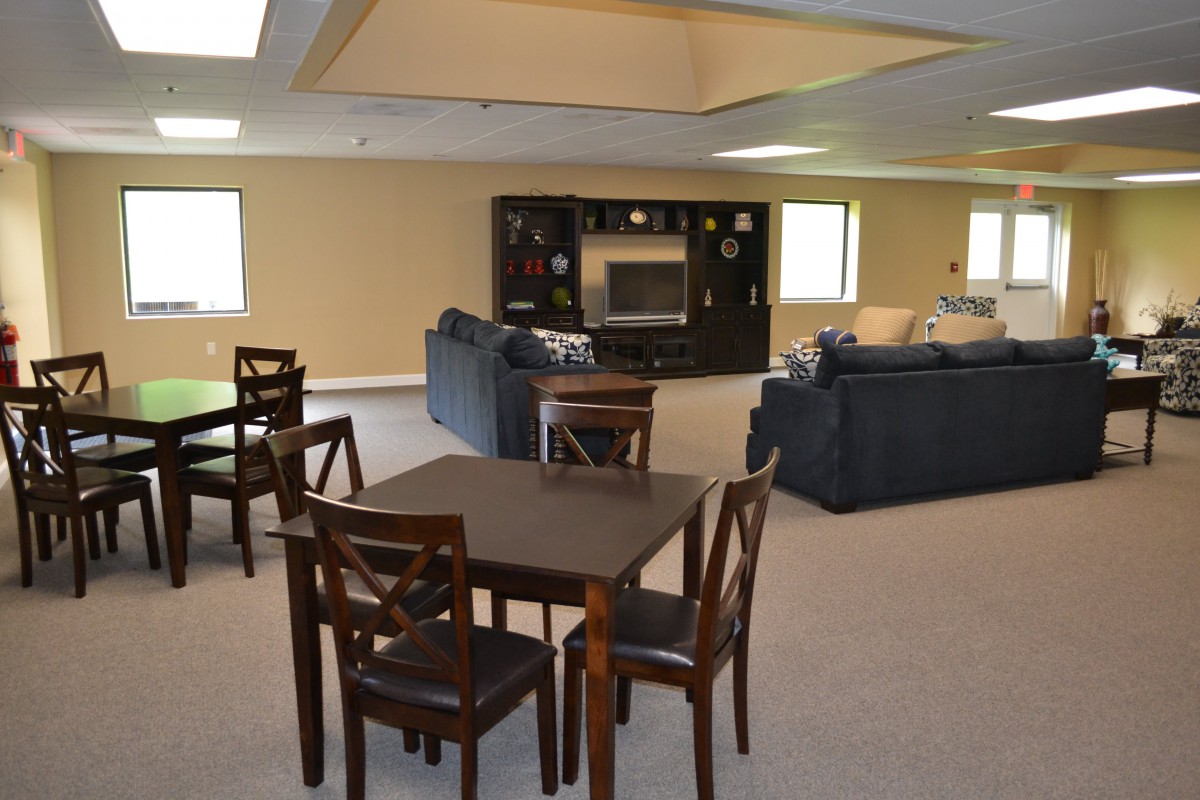 A spacious basement living area featuring comfortable seating and a table setup.