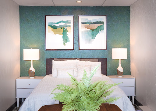 A serene and stylish bedroom featuring a calming teal wall, contemporary artwork, and inviting furnishings.