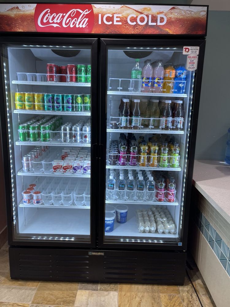 A refrigerator displaying a variety of beverages, including cans and bottles.
