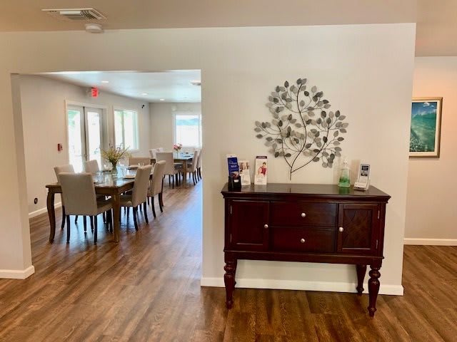 A cozy dining area with a wooden floor, featuring a side table adorned with decorative wall art.