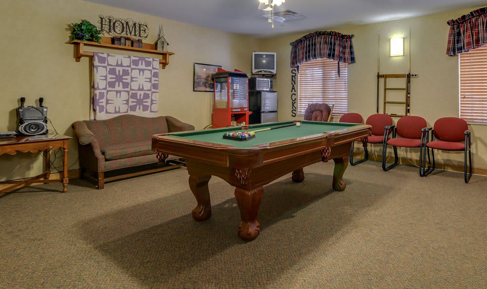 A cozy indoor game room featuring a pool table, sofa, and chairs.