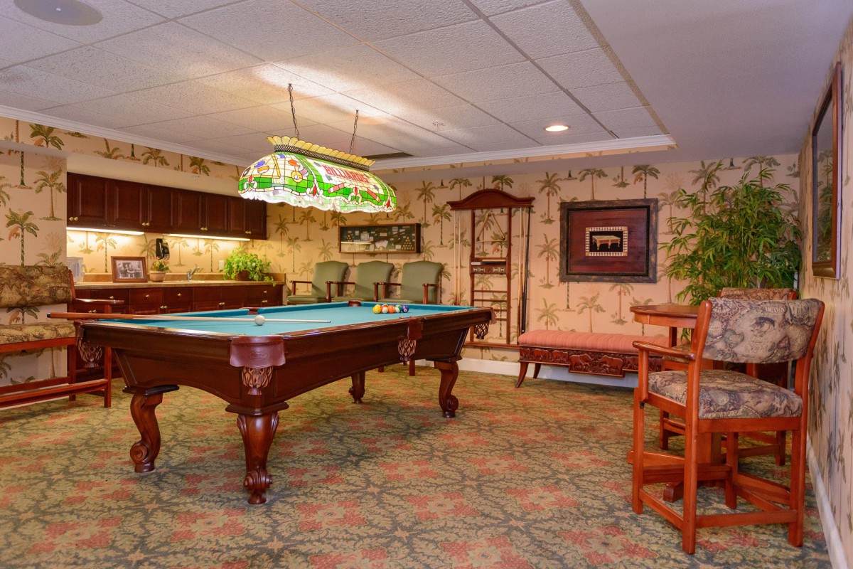 A vintage-style billiard room featuring a classic pool table and ornate lighting.