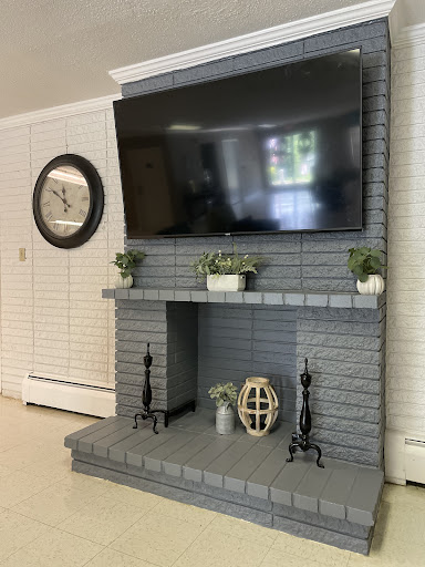 A modern living room setup featuring a large flat-screen TV mounted above a stylish gray brick fireplace.