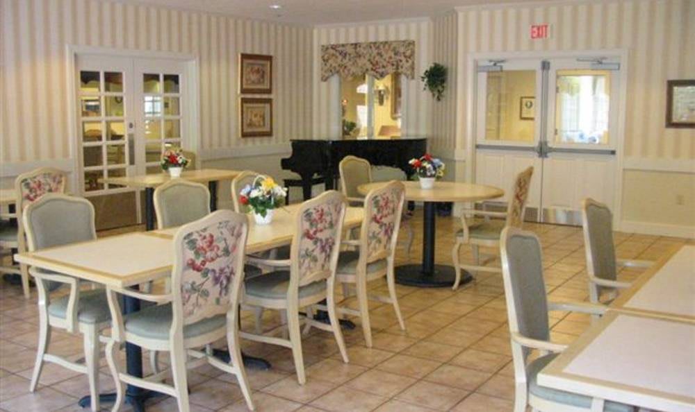 A cozy dining area with floral chairs and a piano in the background.