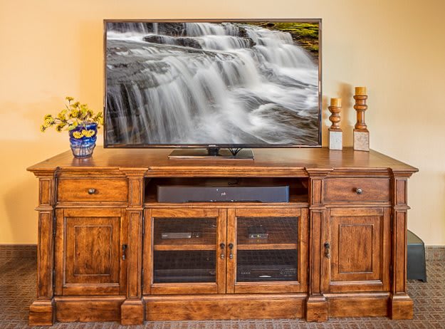 A cozy living room setup featuring a television on a wooden entertainment center, displaying a serene waterfall image.