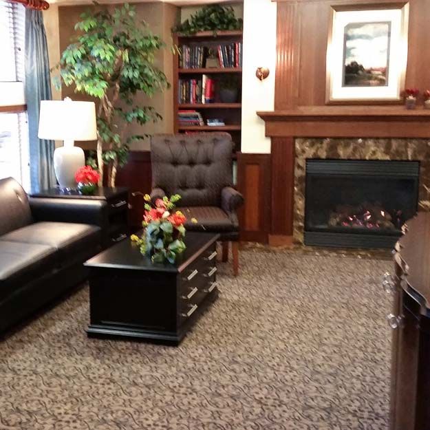 A cozy living room featuring a sofa, fireplace, bookshelf, and decorative elements.