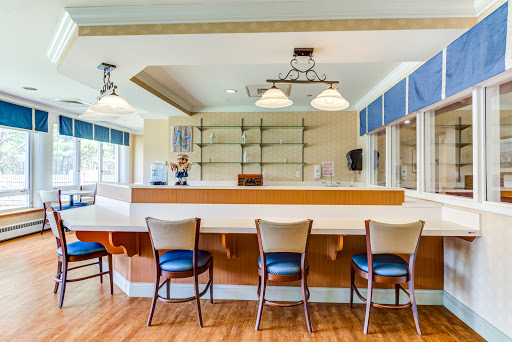 A modern bar setting with a clean design, featuring seating and ample natural light.