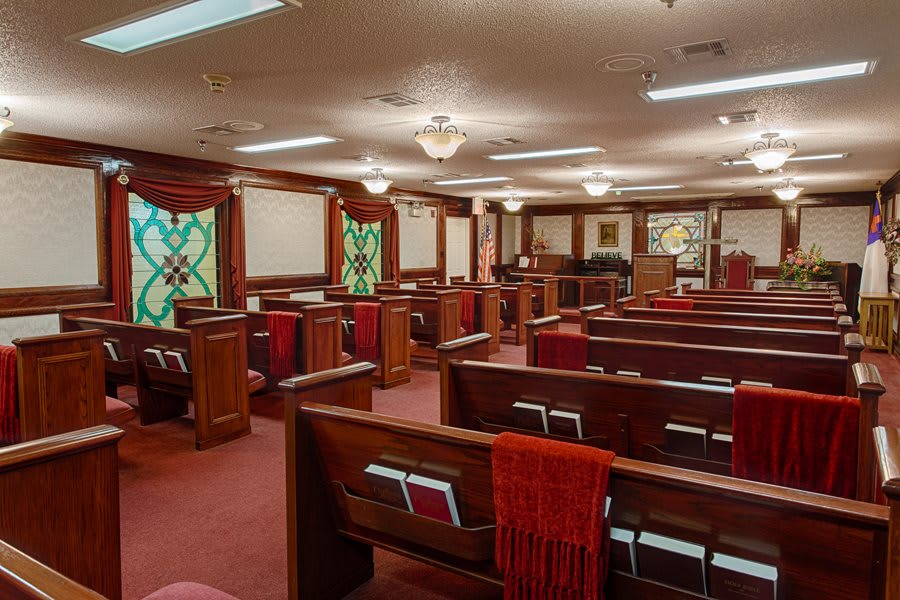 Interior view of a church with wooden pews and stained glass windows.