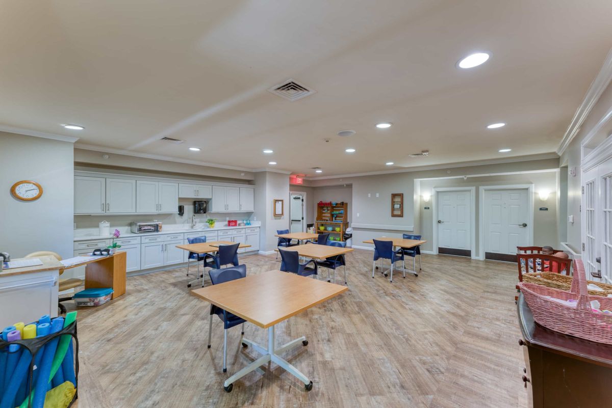 An empty classroom with tables and chairs arranged neatly.