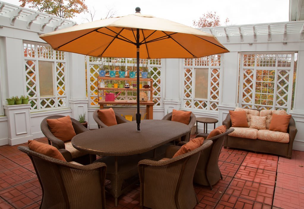 A cozy outdoor patio with a large table, comfortable seating, and an umbrella for shade.