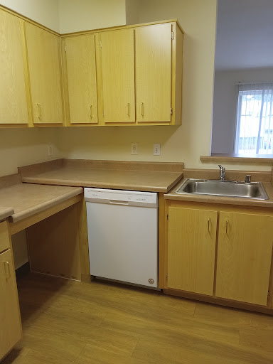 A compact kitchen featuring yellow cabinets, a countertop, sink, and a dishwasher.