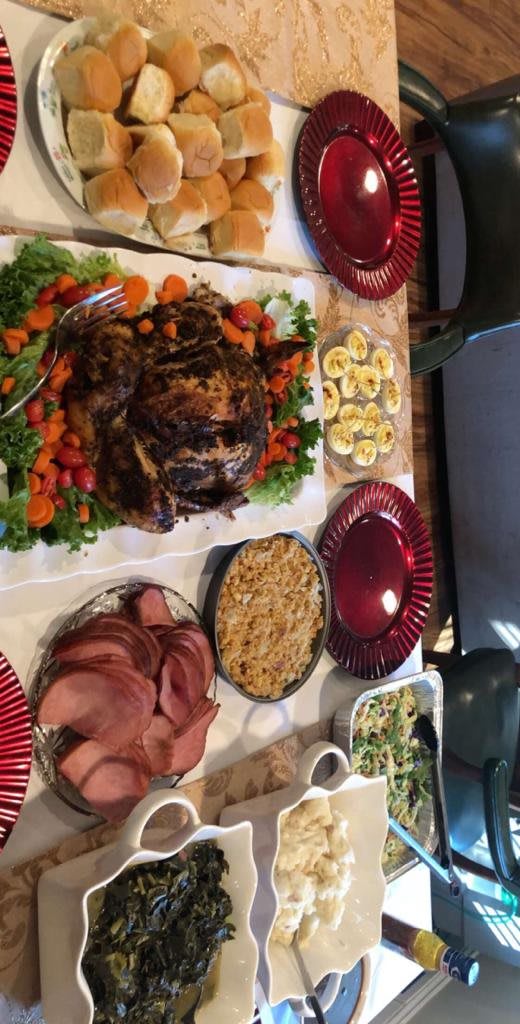 A festive holiday dinner spread featuring roast turkey, sliced ham, stuffing, deviled eggs, and green bean casserole.