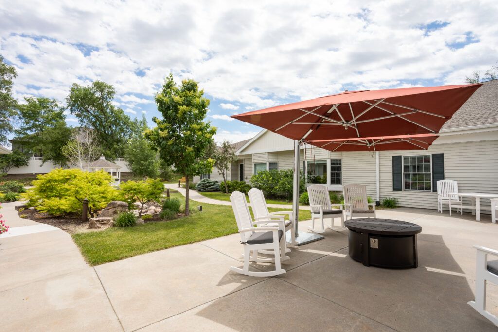 A cozy patio setup with chairs and an umbrella, surrounded by a well-maintained garden on a sunny day.
