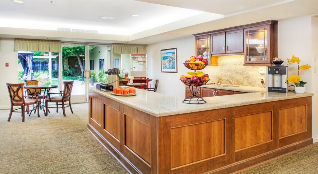 A modern kitchen interior featuring a spacious countertop and wooden cabinetry, adorned with fruit displays.