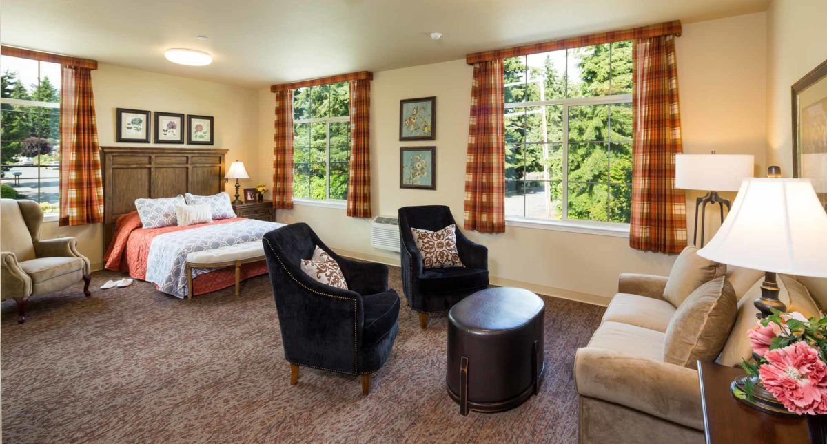 A cozy living area combined with a bedroom featuring comfortable seating and large windows.