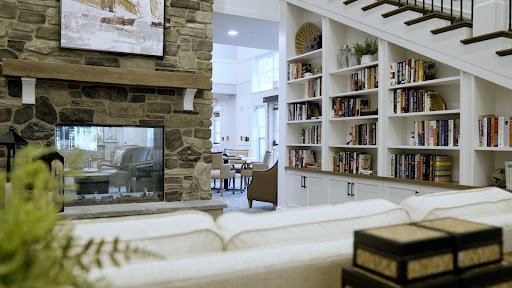 A cozy living room featuring a stone fireplace and built-in bookshelves, illuminated by natural light.