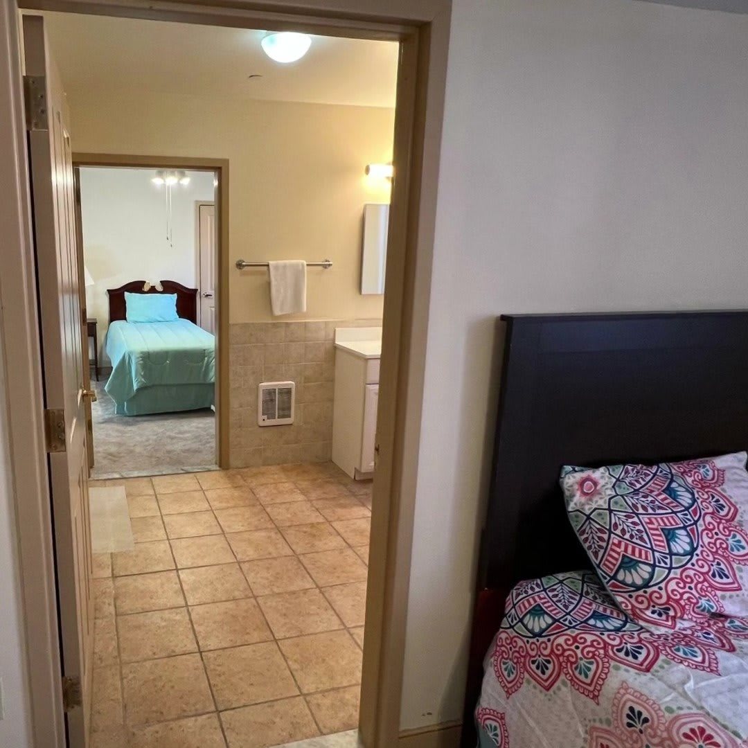 Two adjoining bedrooms with colorful bedding, separated by a doorway.