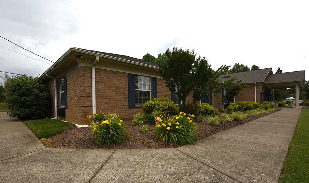 A brick house with well-maintained landscaping and colorful flowers.