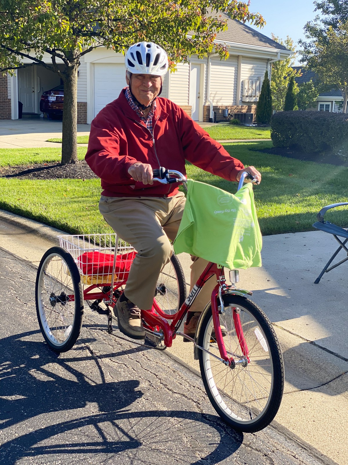 A person riding a tricycle with a helmet on in a residential area.