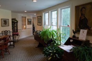 A well-lit hallway with plants and large windows on one side.