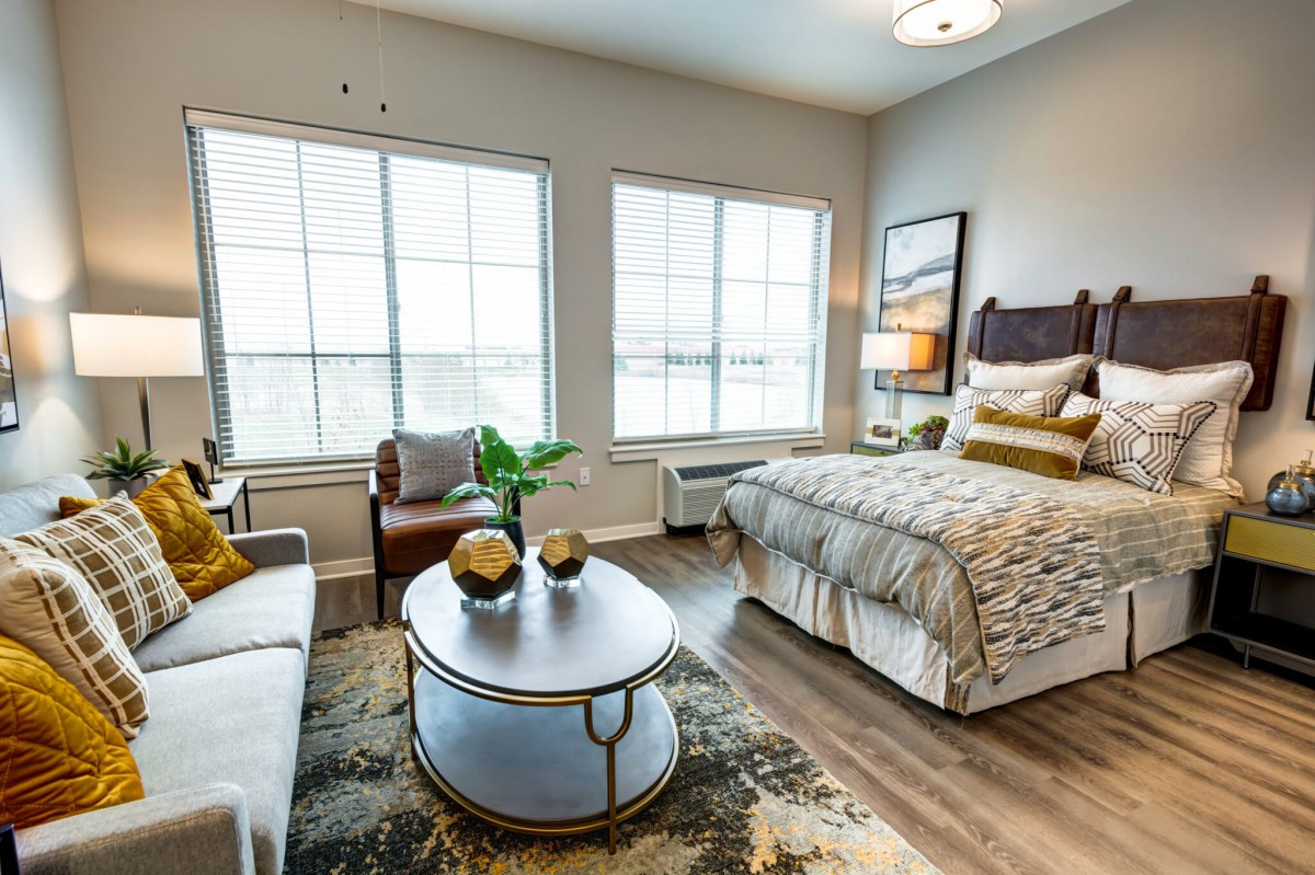 A modern and well-lit bedroom featuring a cozy bed, stylish furniture, and large windows allowing natural light to fill the space.