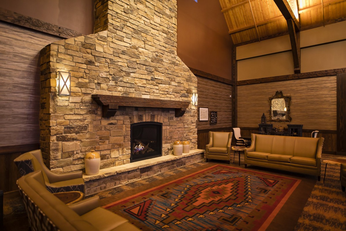A cozy living room with a stone fireplace, warm lighting, and comfortable seating.