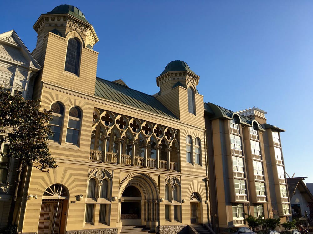 A historic building featuring intricate arches and domed towers under a clear blue sky.