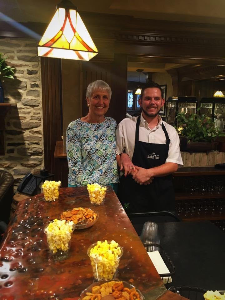 Two people standing in a restaurant setting, with bowls of popcorn on the counter.