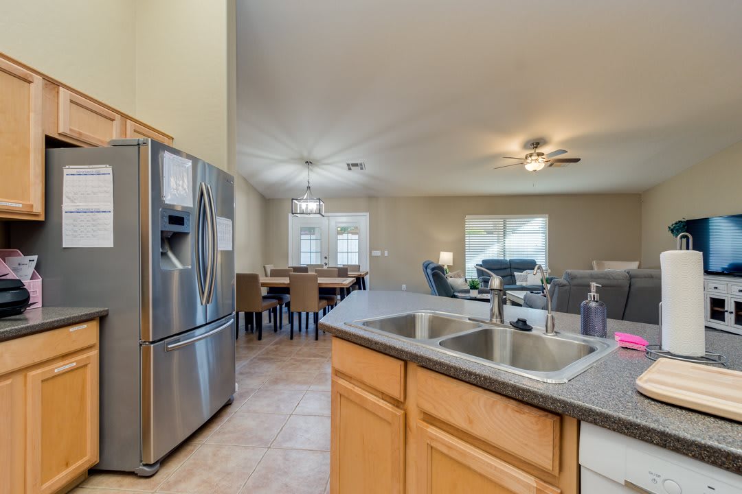 An open floor plan featuring a kitchen with a stainless steel refrigerator, dining area, and living room.