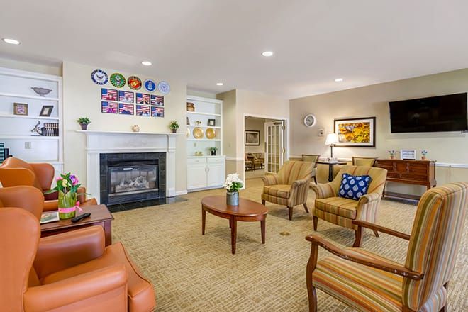 A cozy living room with a fireplace, comfortable seating, and decorative elements on the walls.