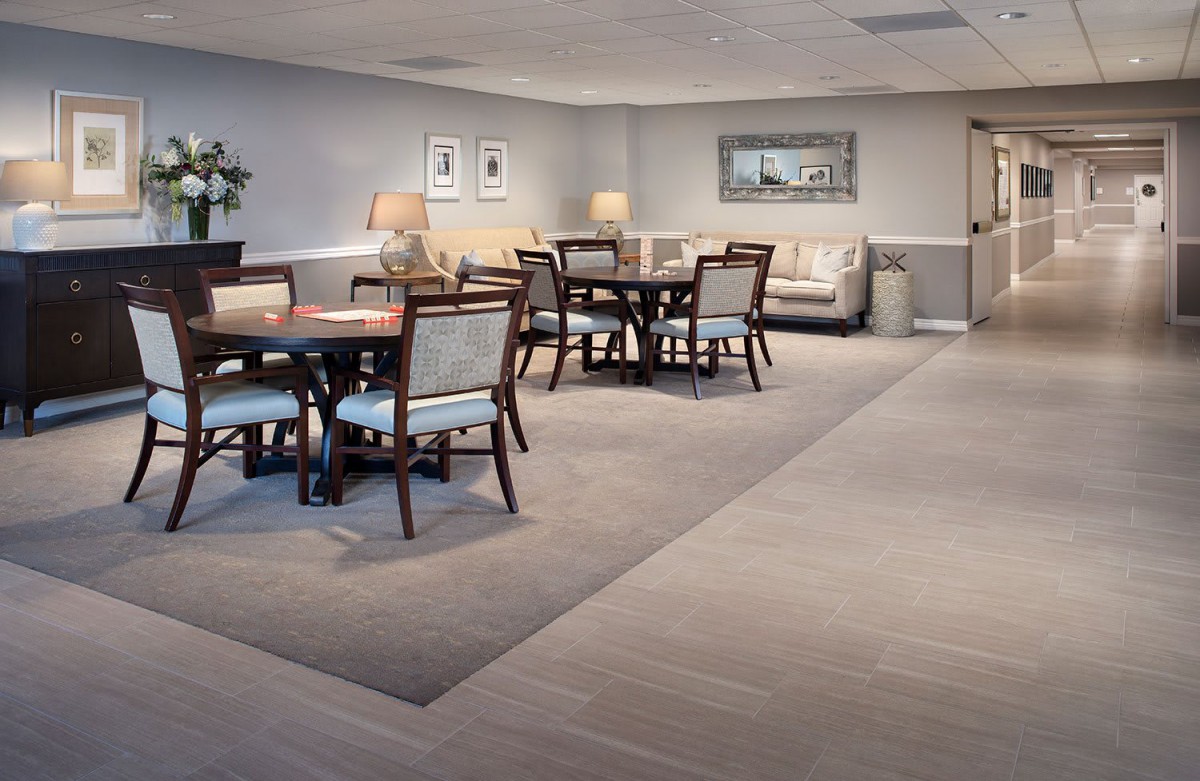 A modern dining area with neatly arranged tables and chairs, accented by soft lighting and a comfortable seating corner.