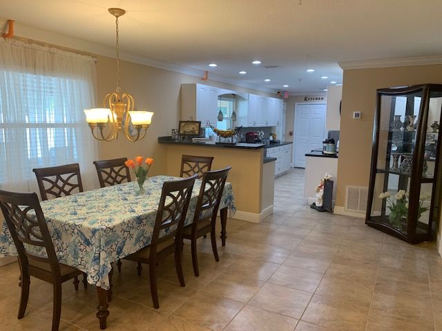 A cozy dining area with a table set for six, leading into an open kitchen space.