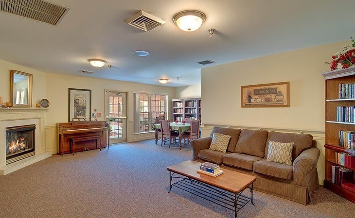 A cozy living room with a sofa, coffee table, and a dining area in the background.