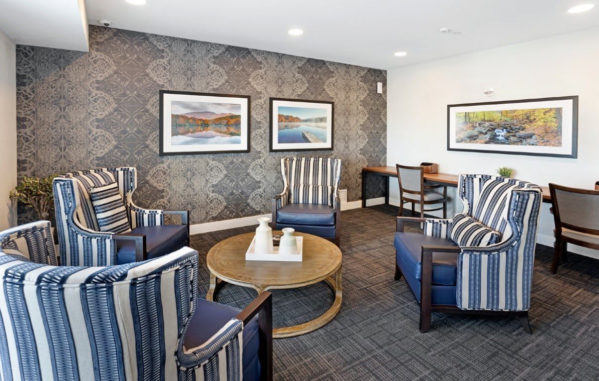 A stylish living room featuring striped armchairs, a round coffee table, and framed artwork on the wall.