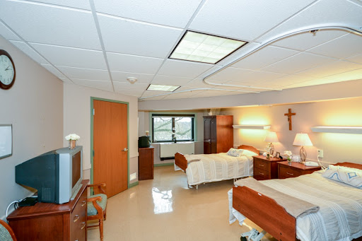 A serene and well-organized patient room in a hospital, featuring two beds and ample natural light.