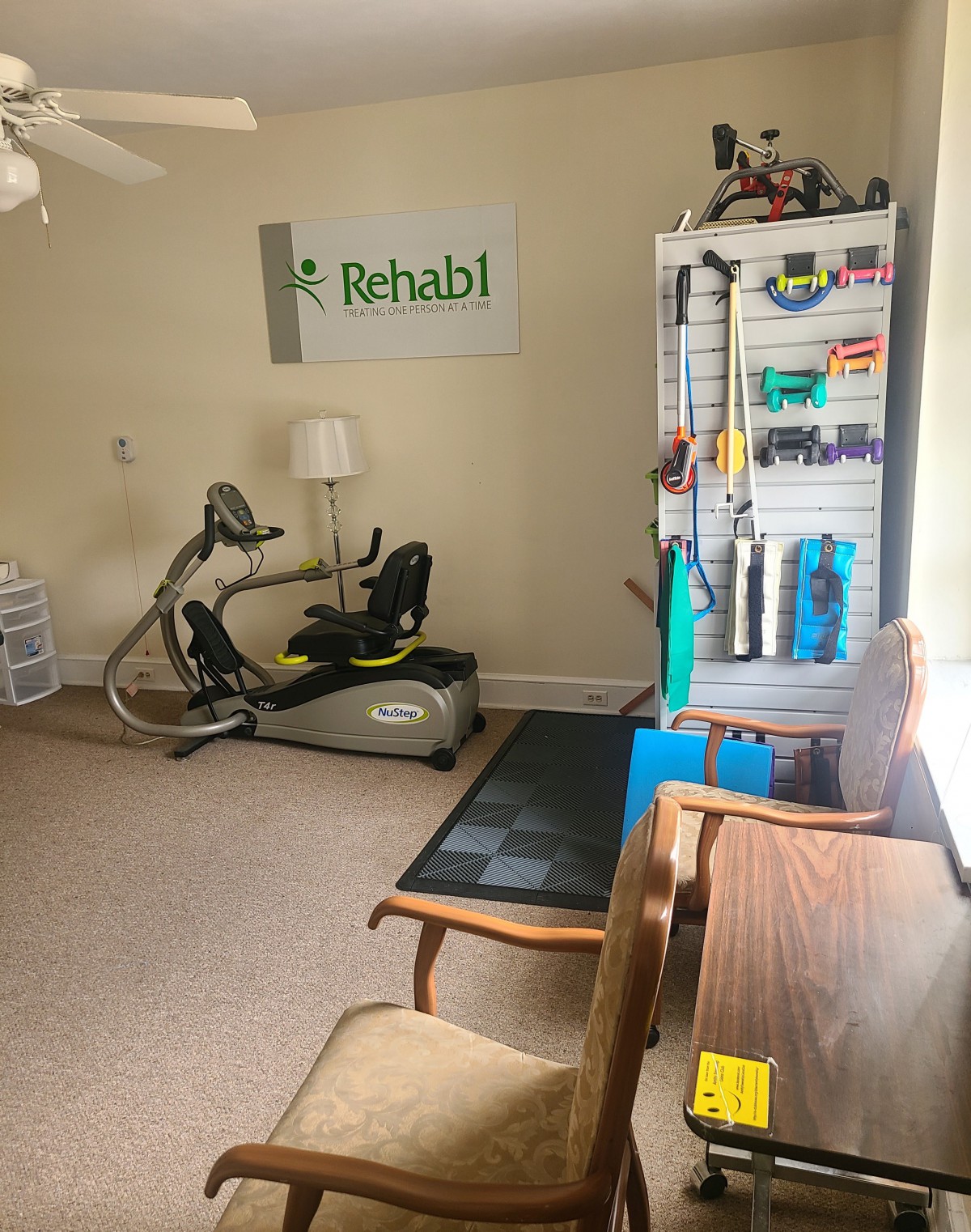 A rehabilitation room featuring an exercise bike, therapy equipment, and a comfortable seating area.
