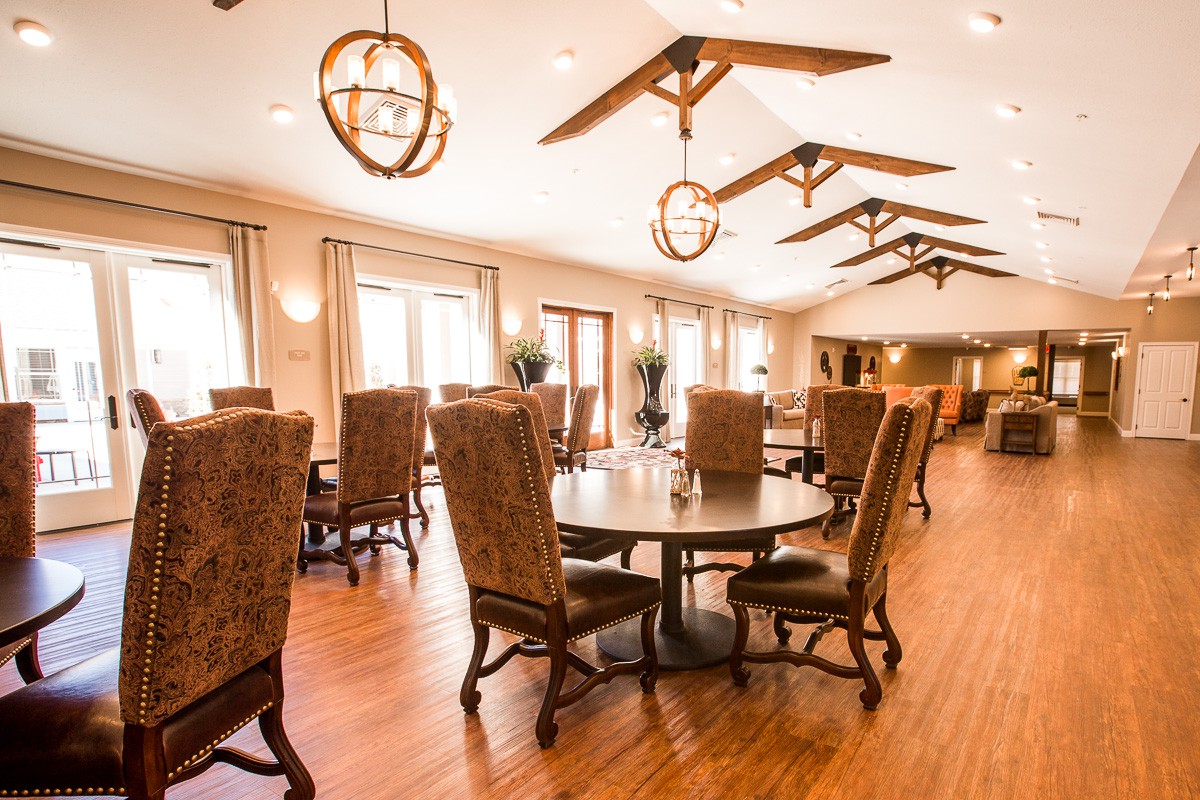 A spacious and elegantly furnished dining room with wooden floors and sophisticated lighting.